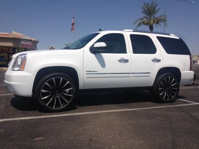 A white suv with black wheels is parked in a parking lot
