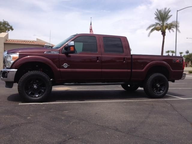 A red truck is parked in a parking lot with a palm tree in the background