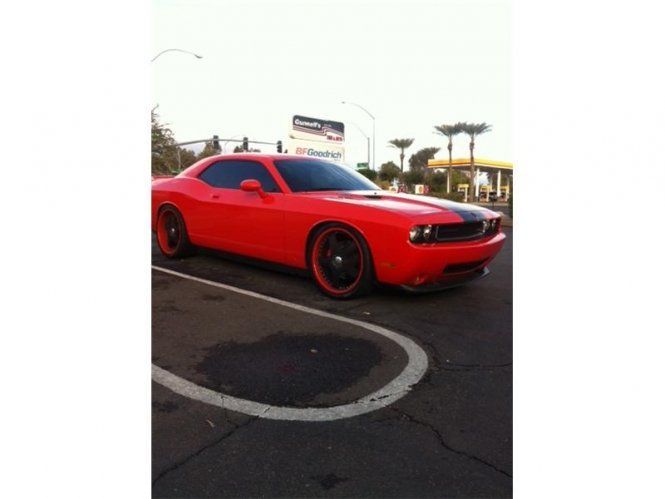 A red dodge challenger is parked in a parking lot