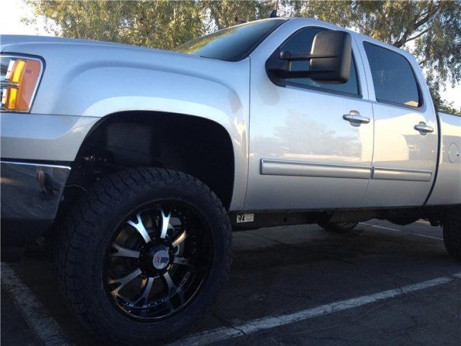 A silver truck with black wheels is parked in a parking lot