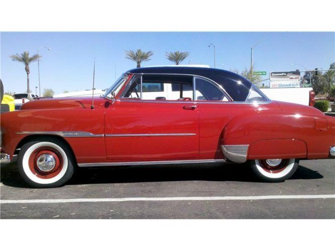 A red car with white tires is parked in a parking lot