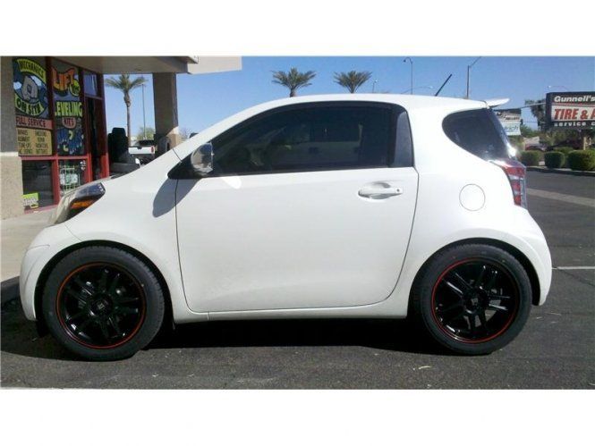 A white car with black wheels is parked in a parking lot