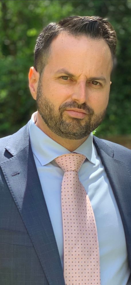 A man with a beard is wearing a suit and tie.
