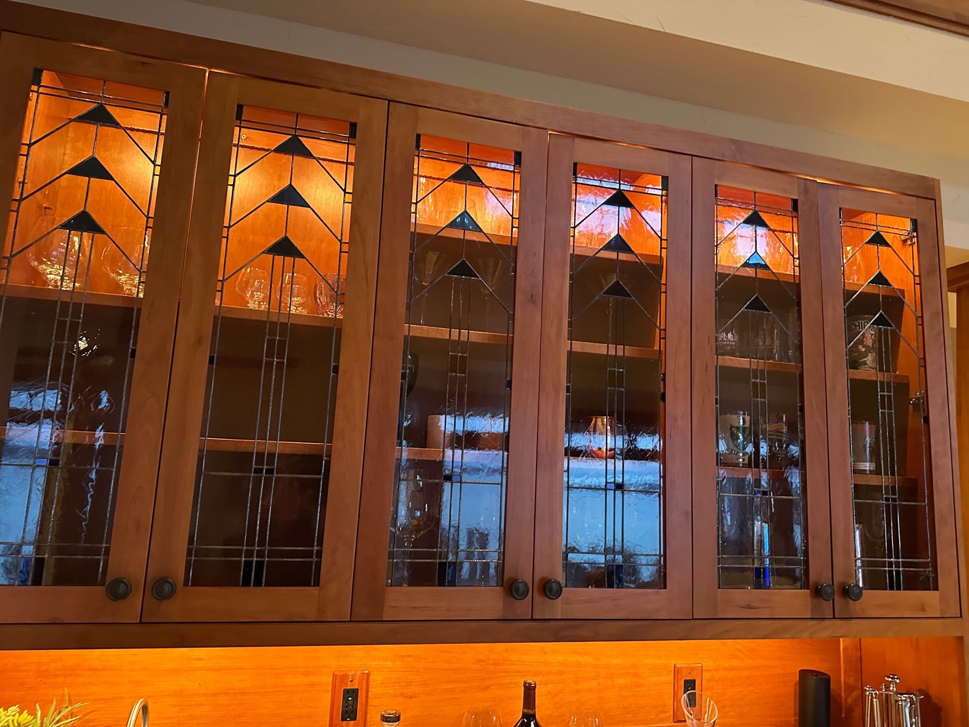 A kitchen cabinet with stained glass doors filled with wine glasses