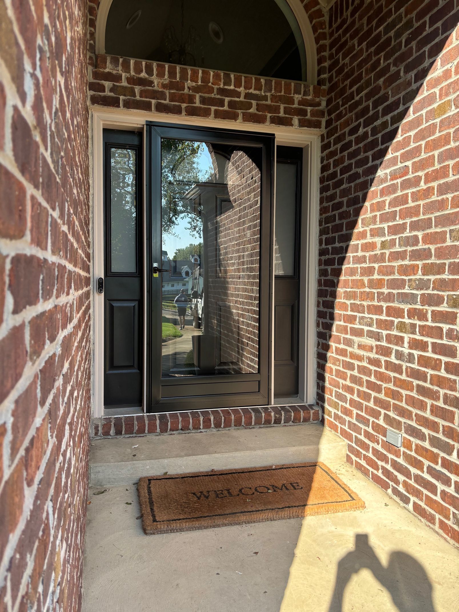 A brick building with a black trimmed glass door.