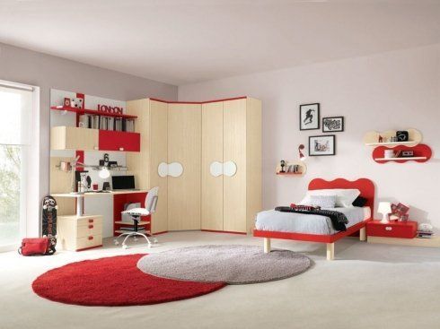 una cameretta con un letto rosso e un armadio angolare beige chiaro