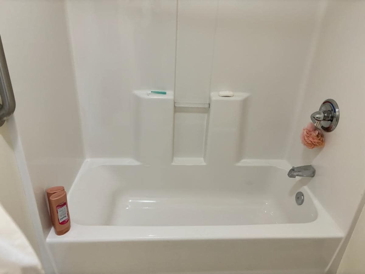 A white bathtub in a bathroom with a shower stall.