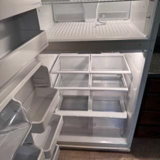 Open, empty refrigerator with shelves and drawers.