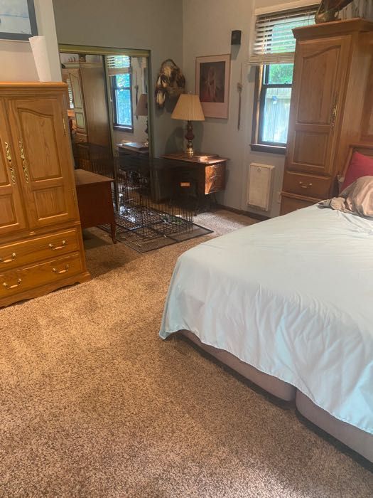 Bedroom with large bed, wooden furniture, and patterned carpet.
