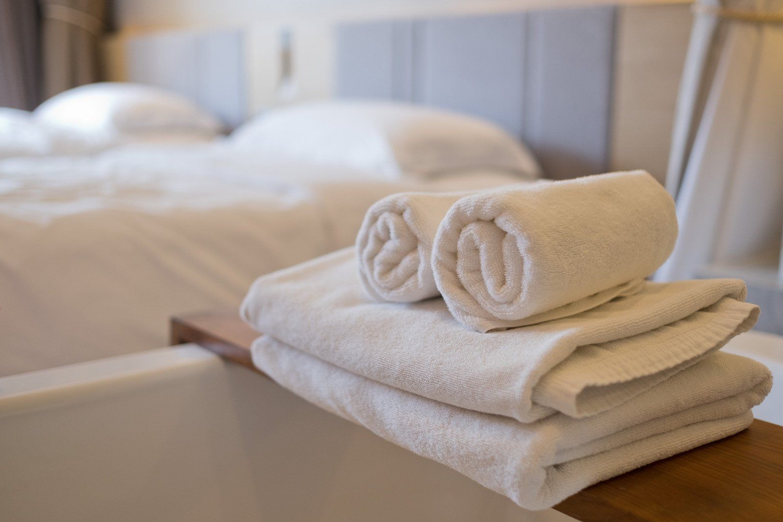 A stack of towels sitting on top of a bathtub in a hotel room.