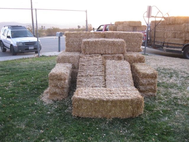 A couch made out of hay bales is sitting in the grass