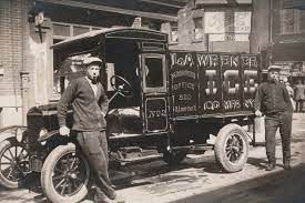 Two men are standing next to a truck in a black and white photo.