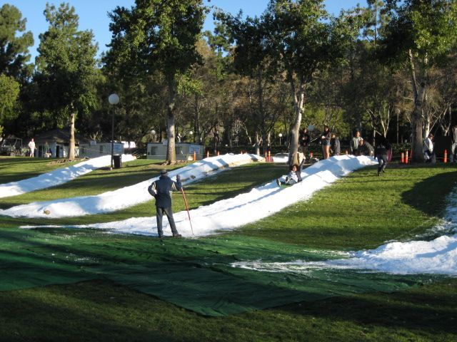 A man is standing in the middle of a grassy field covered in snow.