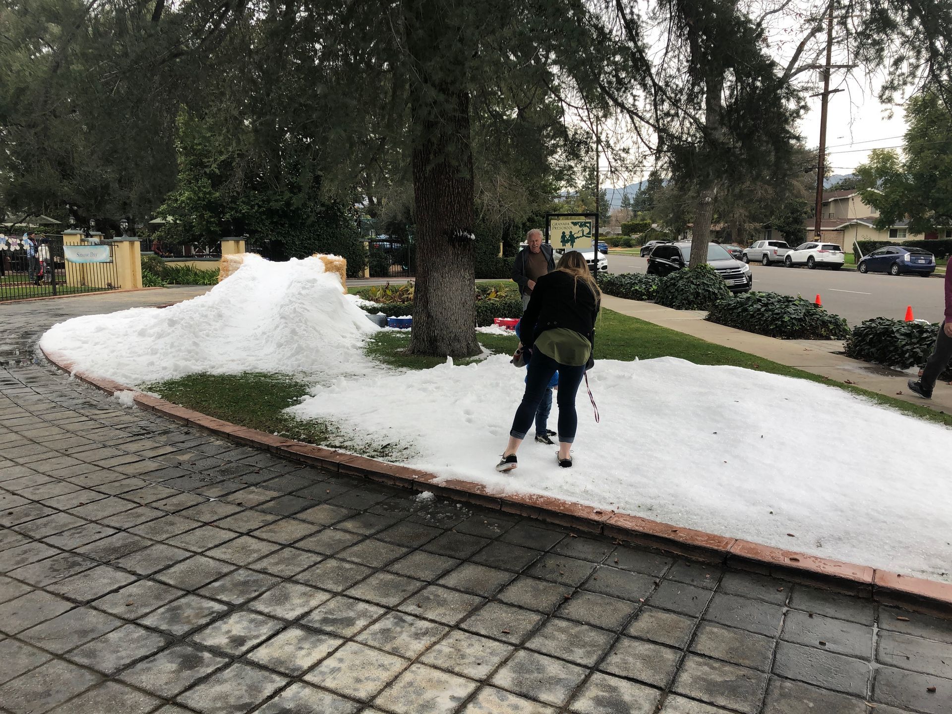 A couple of people standing in front of a pile of snow.