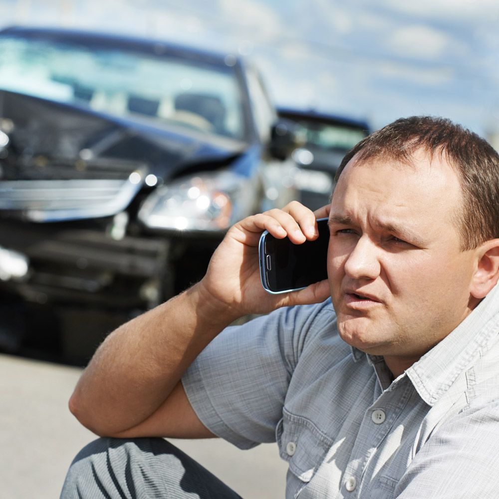A man on the phone in front of a car crash scene