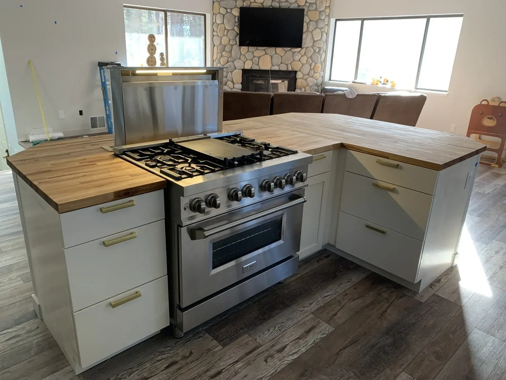 Kitchen island with stainless steel range and butcher-block countertop in a bright, modern kitchen