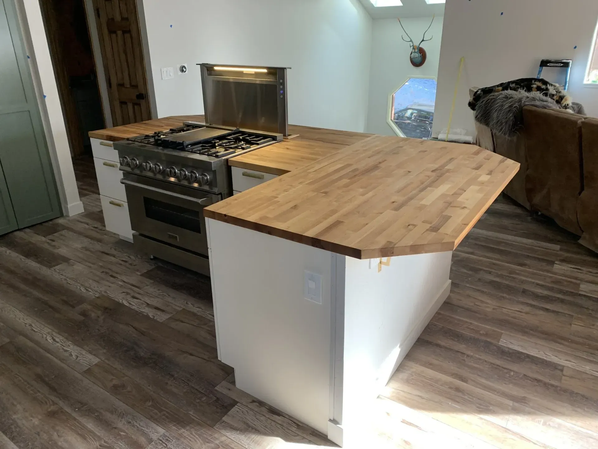 Kitchen with stainless steel stove and a butcher-block island in a room with dark wood floors
