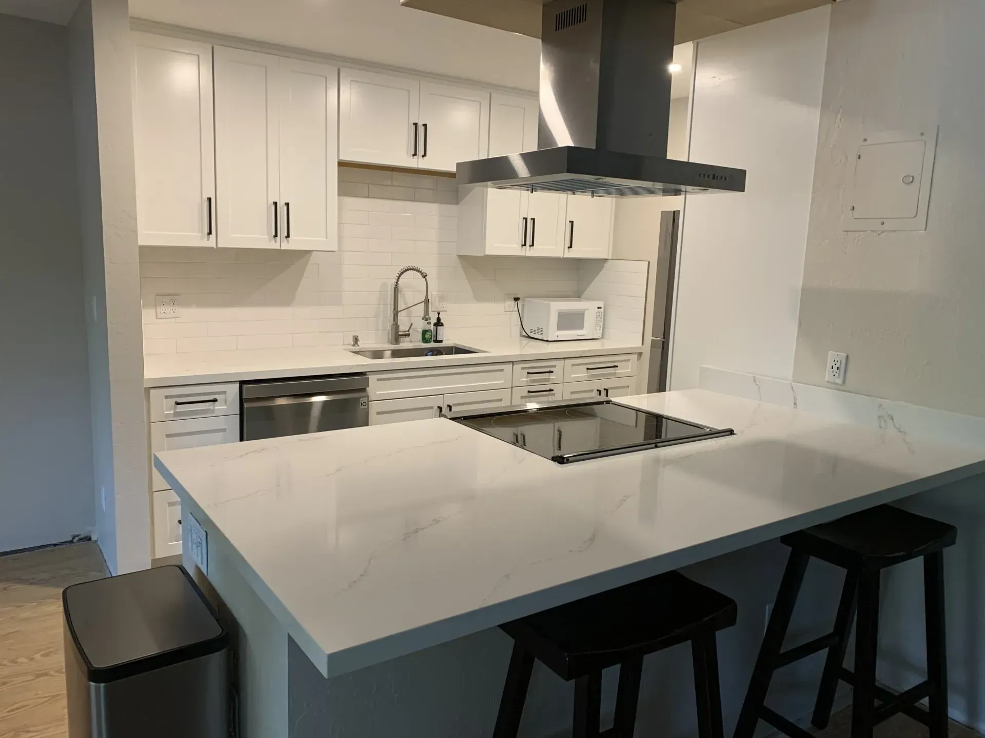 Modern kitchen with white cabinets, large island, black stools, and stainless steel appliances
