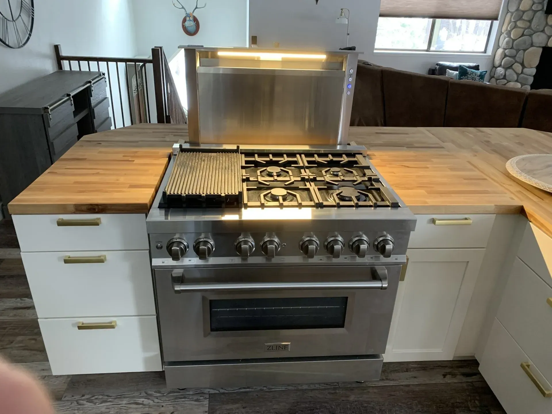 Stainless steel gas range centered between white cabinets and wooden countertops in a kitchen.