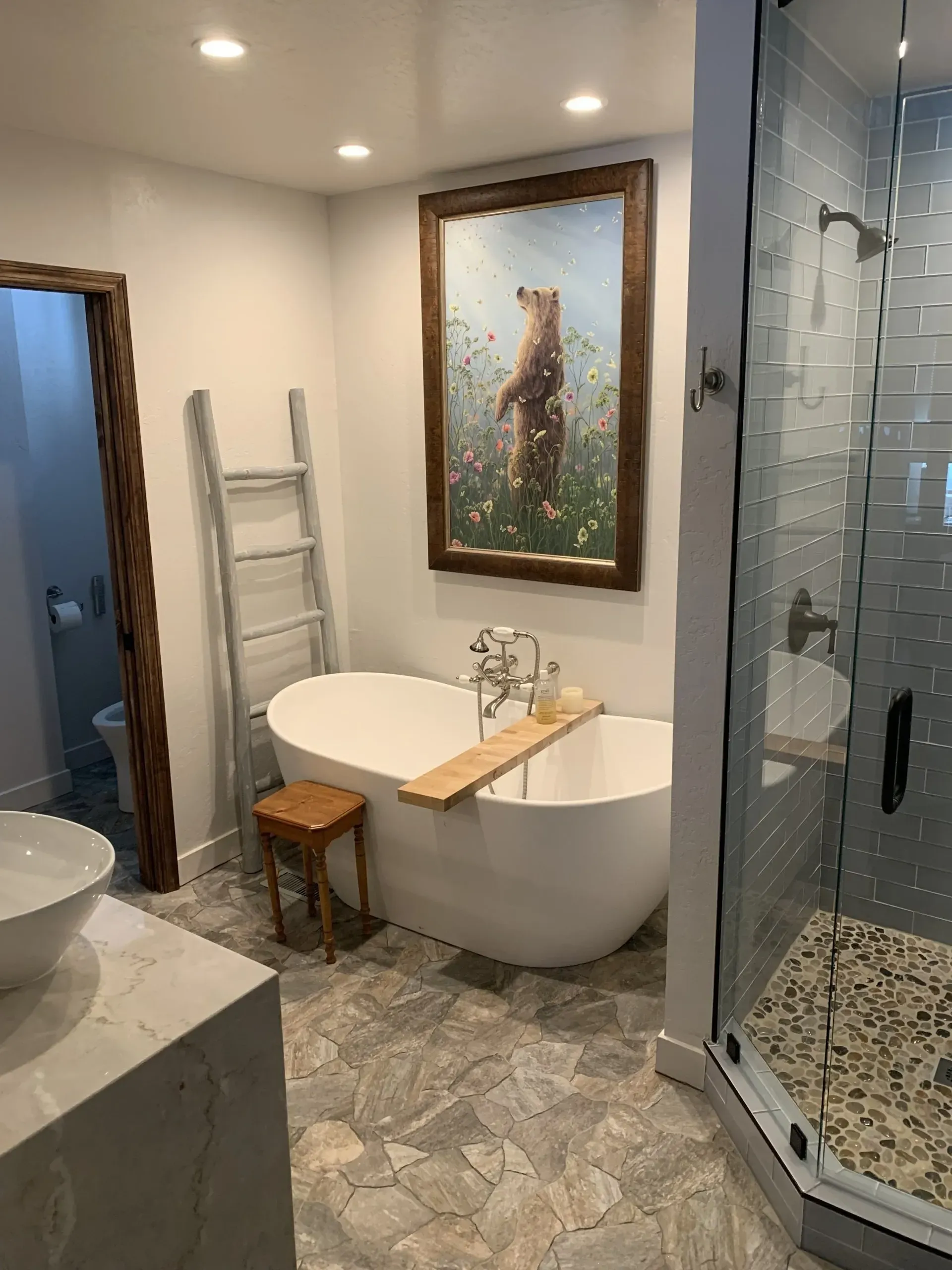 Modern bathroom with freestanding tub, glass shower, marble vanity, and framed wall art.