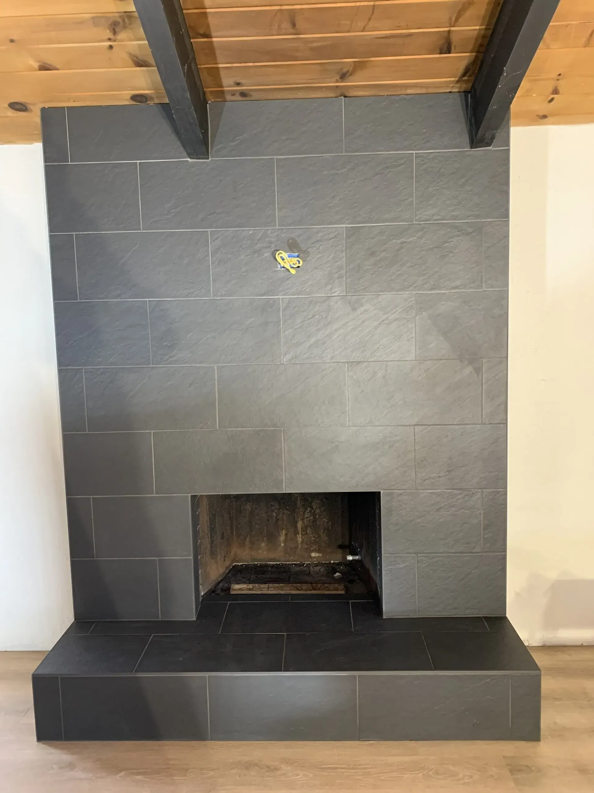 Black-tiled fireplace with a raised hearth and wood-beamed ceiling above.