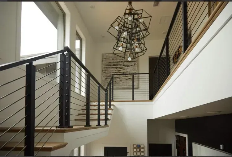 Modern foyer with open staircase, black railings, and hanging geometric light fixture