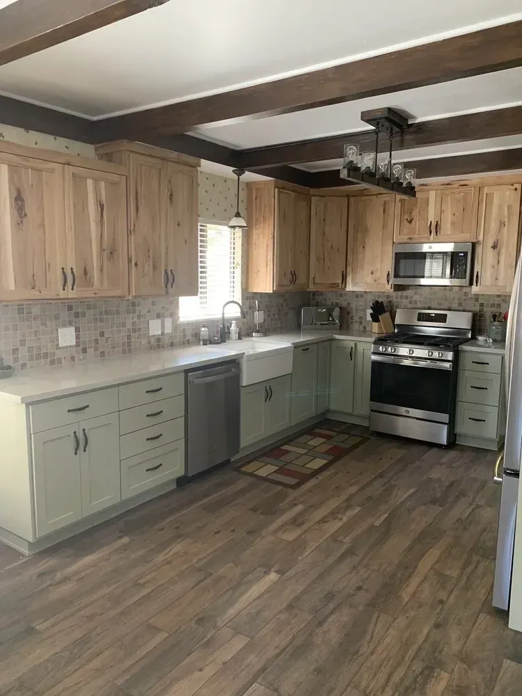 Bright kitchen with wood cabinets, sage lower cabinets, stainless appliances, and a large island.