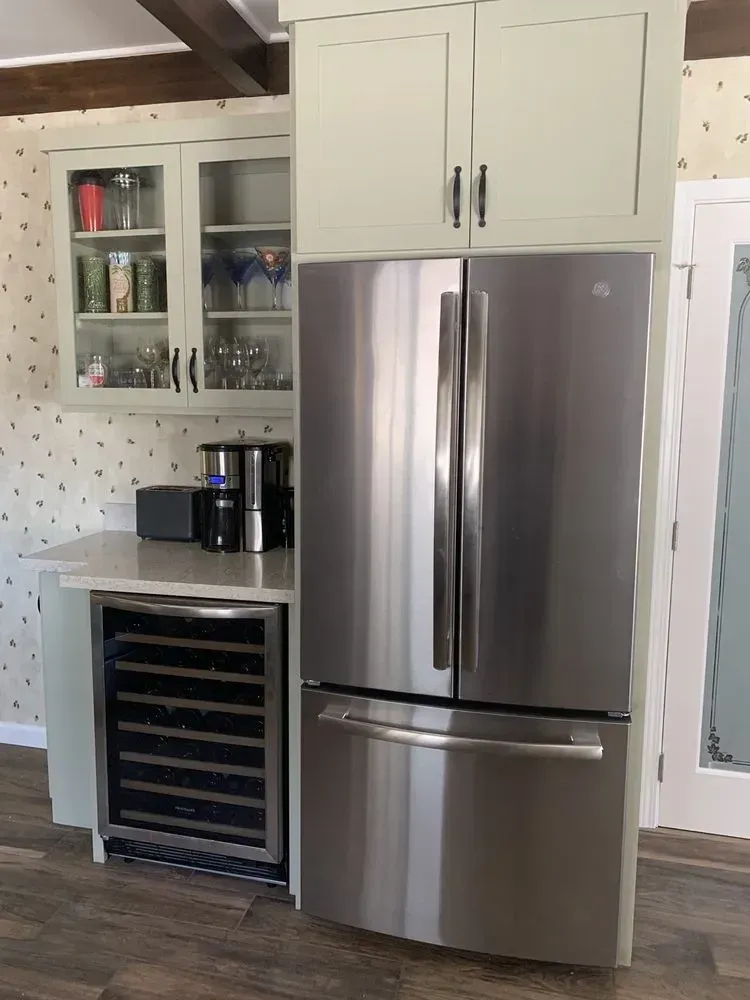 Modern kitchen with stainless steel refrigerator, white cabinets, and a wine rack.