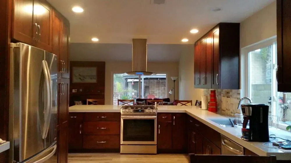 Modern kitchen with stainless steel appliances, dark wood cabinets, and a window over the countertop.
