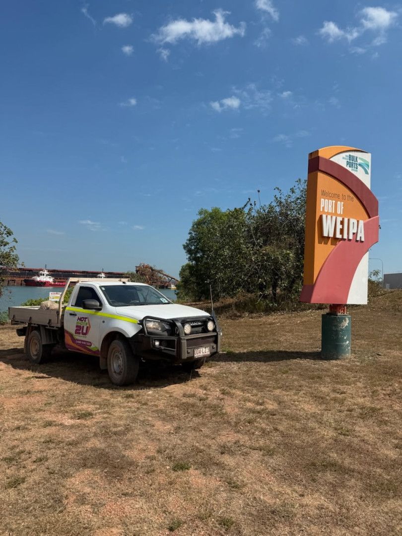 A Delivery Man Is Giving a Box to A Woman in Front of A Van — Hot Shots 2 U In Townsville, QLD