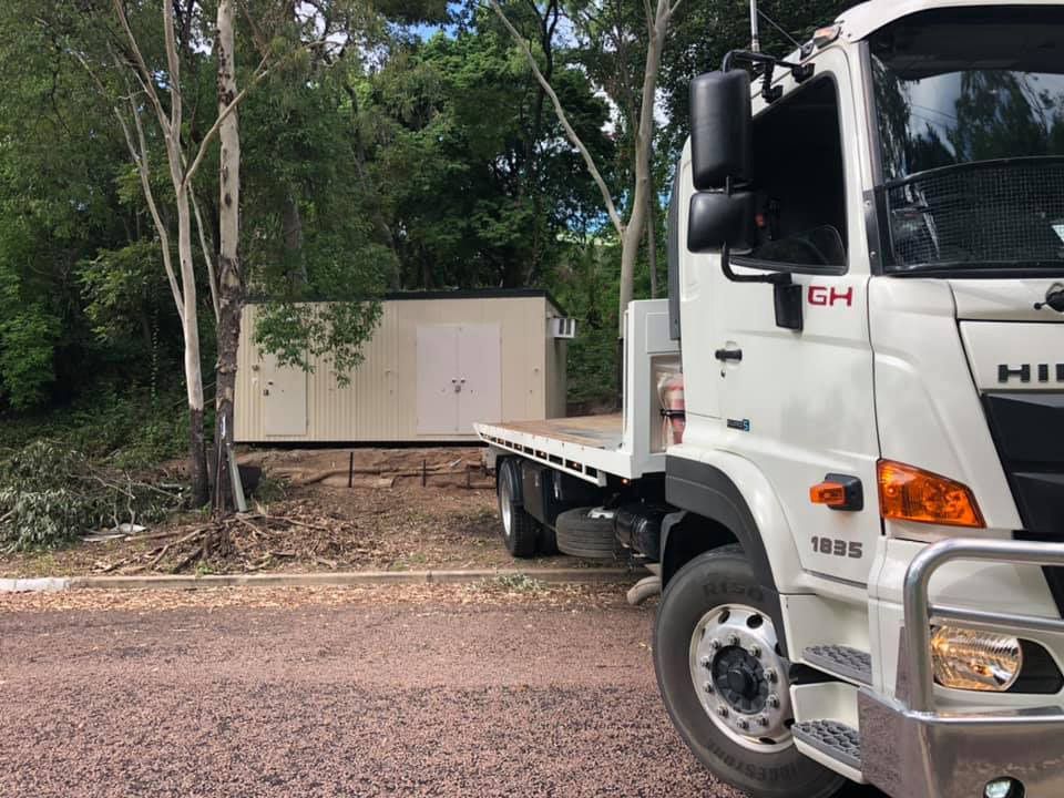 White Truck With Flatbed Next to a Beige Building in a Wooded Area — Hot Shots 2 U In Townsville, QLD
