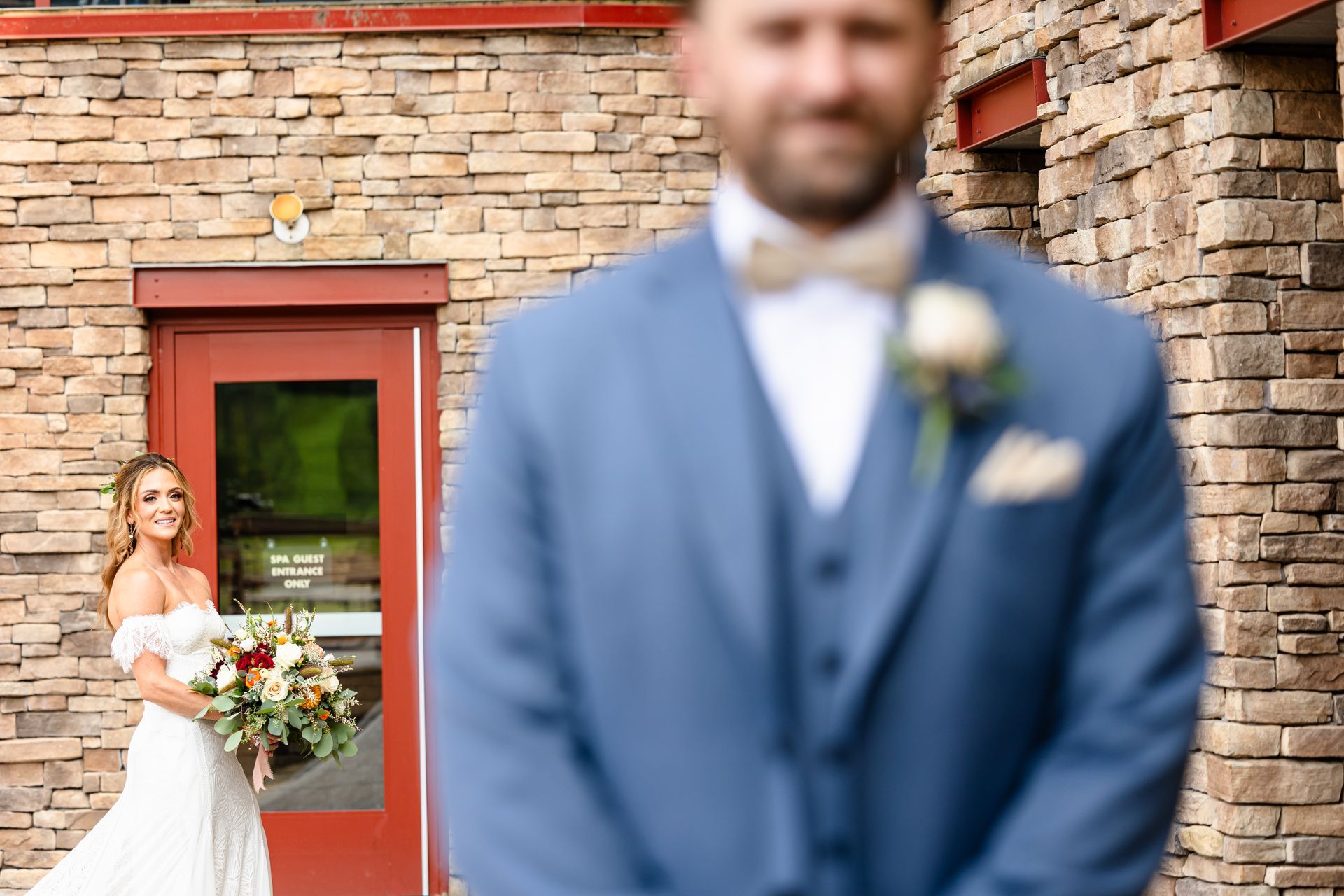 A bride and groom are standing in front of a brick building taken by Ever After Studio.