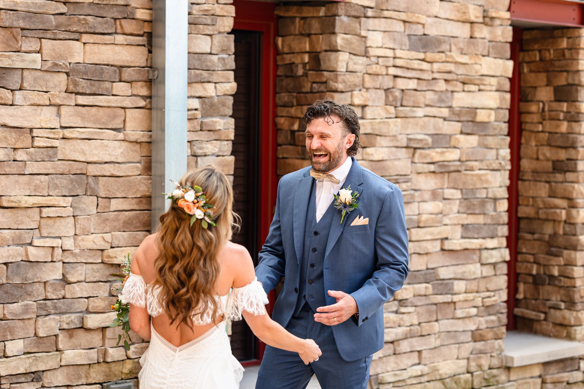 A bride and groom are standing in front of a brick building taken by Ever After Studio.