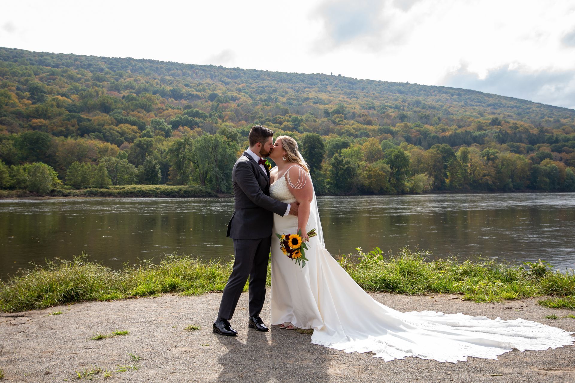 A  photo of a bride and groom kissing in front of a lake taken by Everafter Studio.