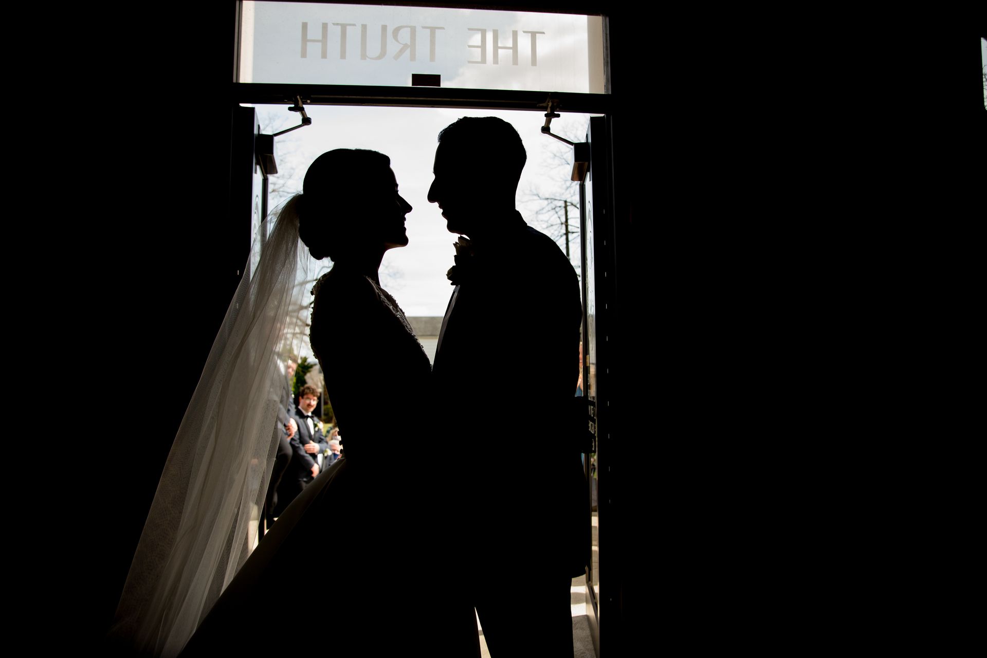 A photo of bride and groom are standing in a doorway looking at each other taken by Ever After Studio.
