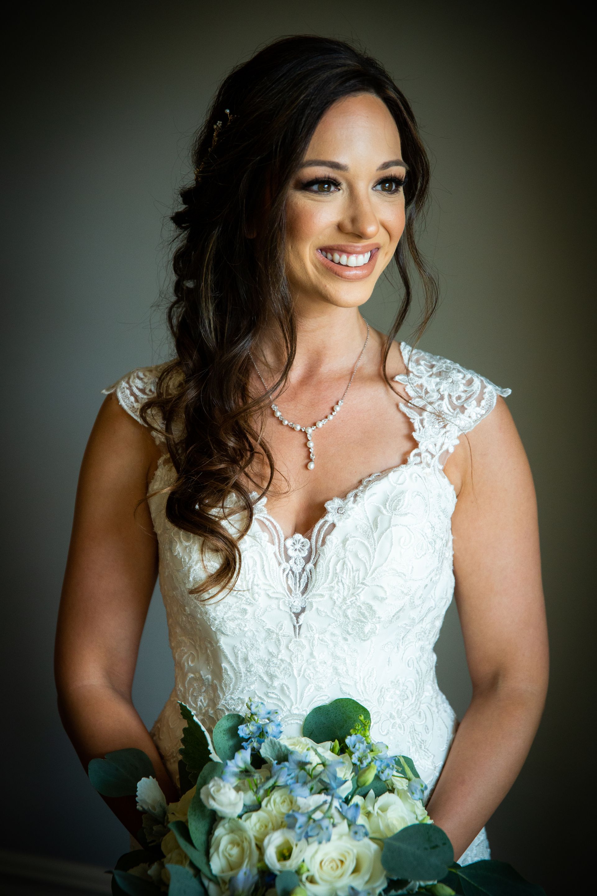 A bride in a wedding dress is holding a bouquet of flowers and smiling taken by Ever After Studio.