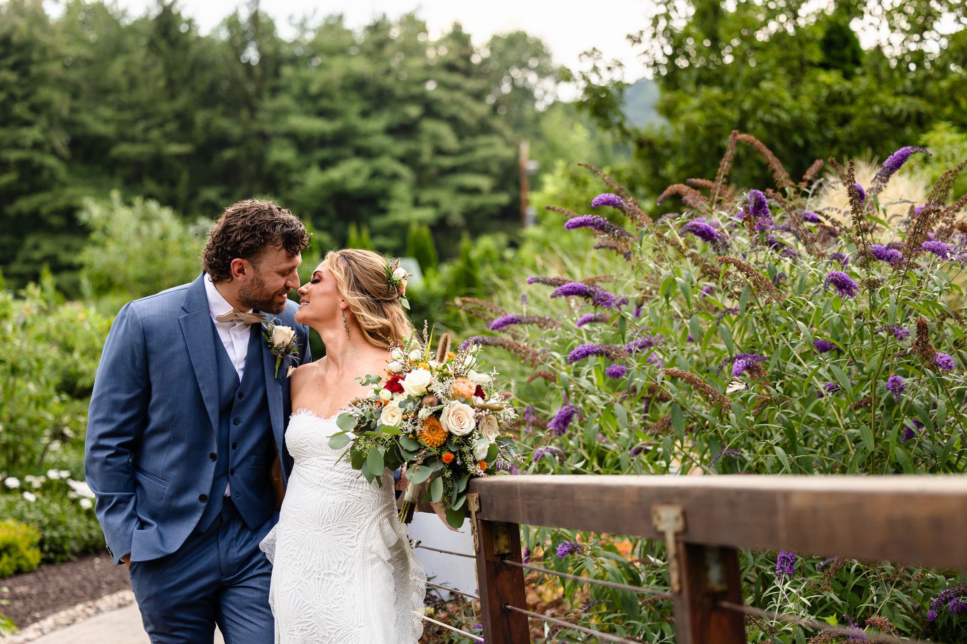 A bride and groom are kissing on a wooden bridge taken by Ever After Studio.
