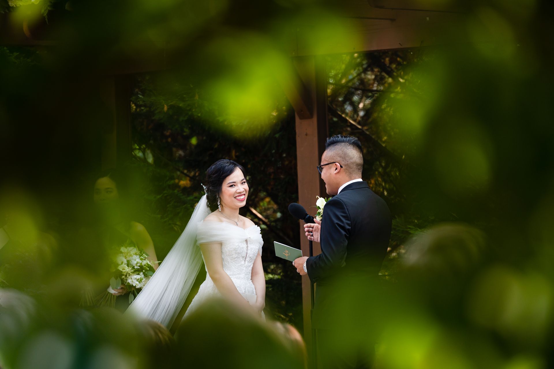 A bride and groom are standing next to each other during their wedding ceremony taken by Ever After Studio.