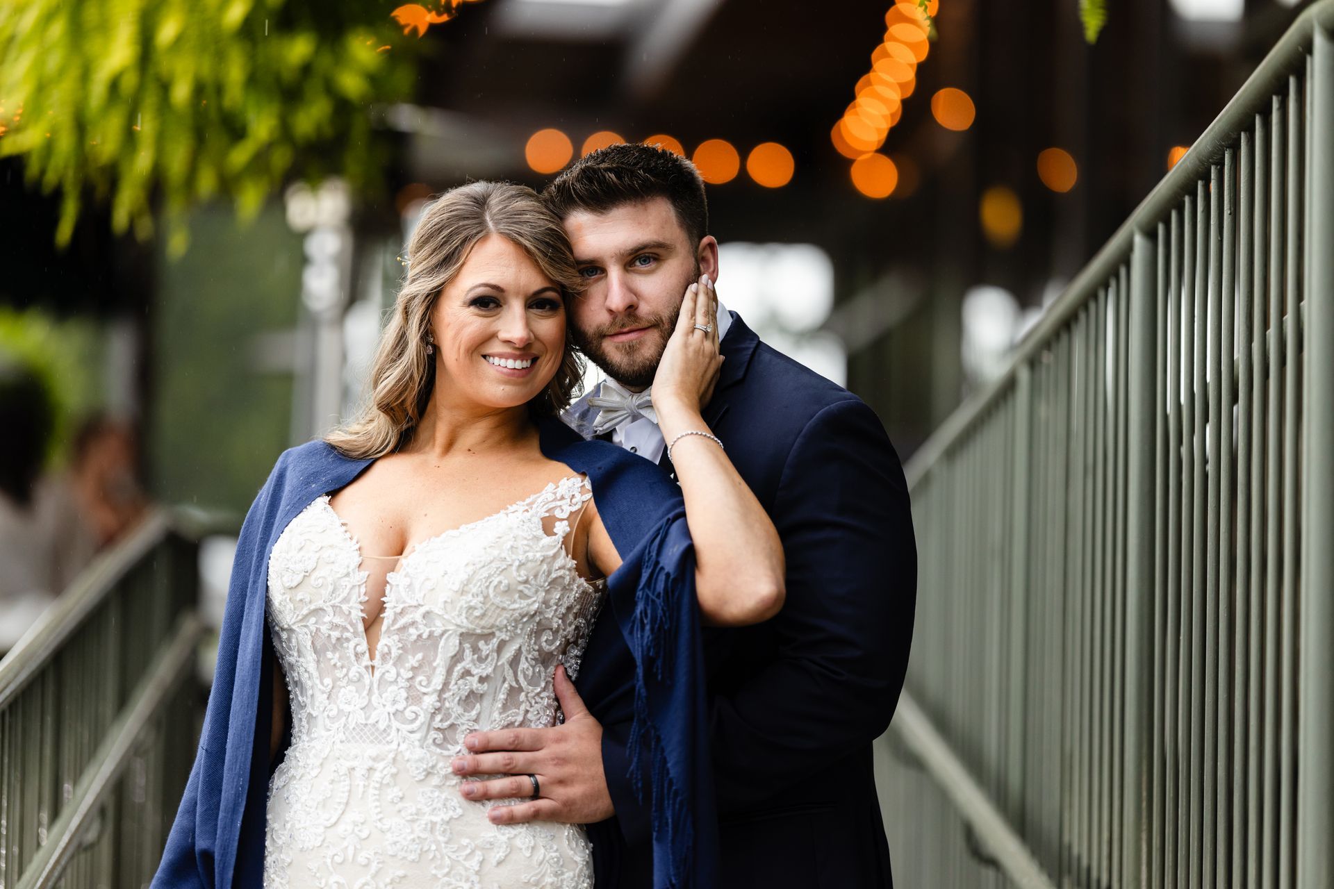 A bride and groom are posing for a picture on a bridge taken by Ever After Studio.