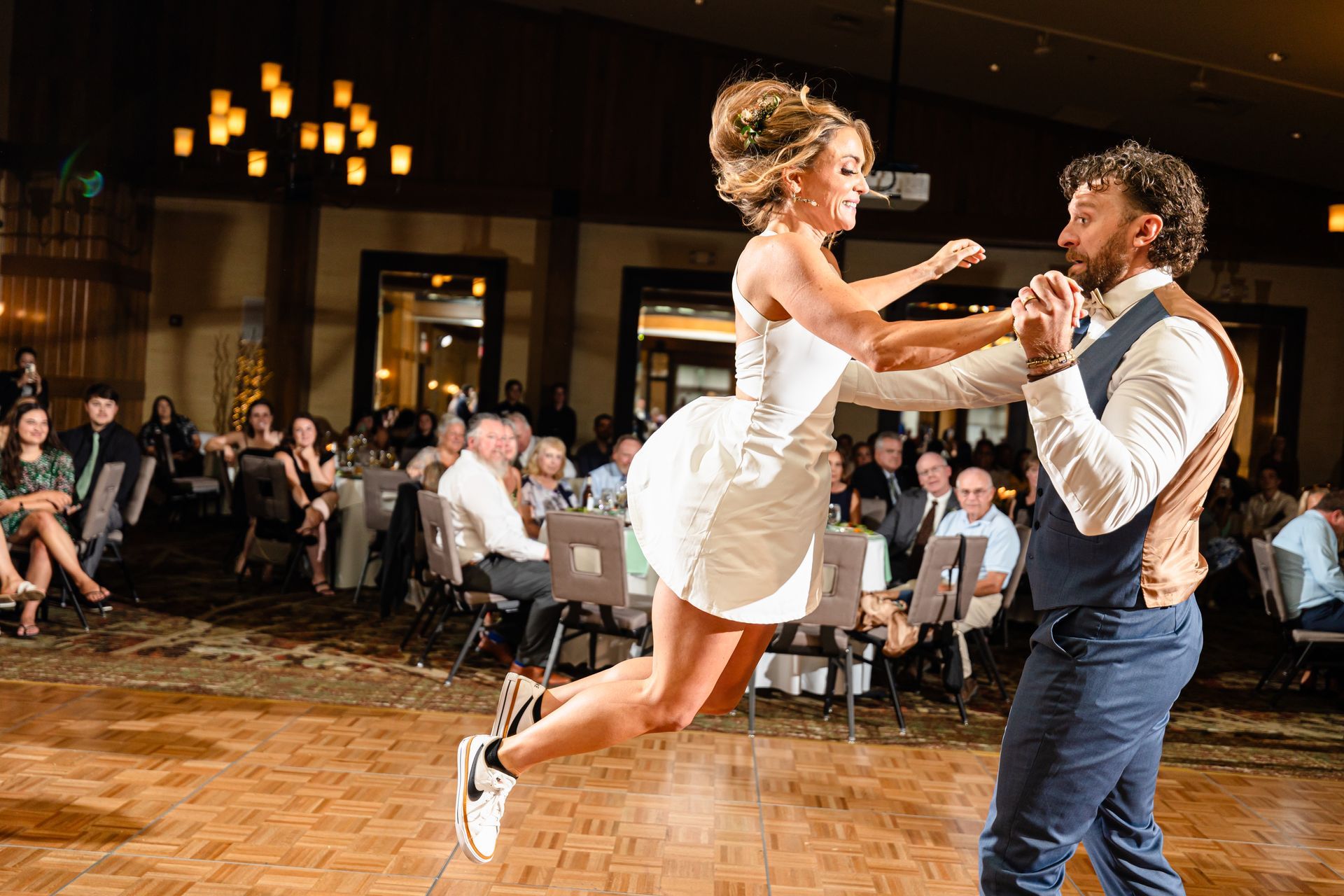 A bride and groom are dancing on a wooden floor at their wedding reception taken by Ever After Studio.