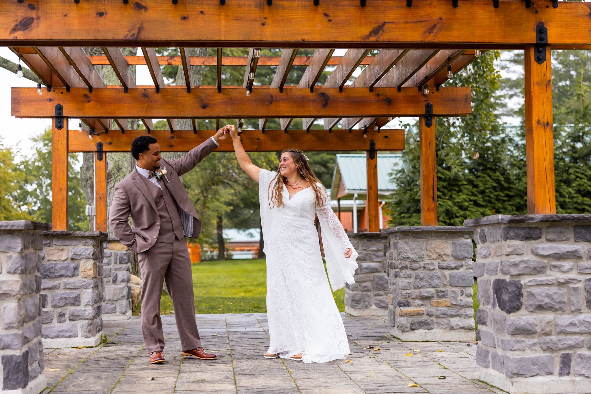 A bride and groom are dancing under a wooden pergola taken by Ever After Studio.