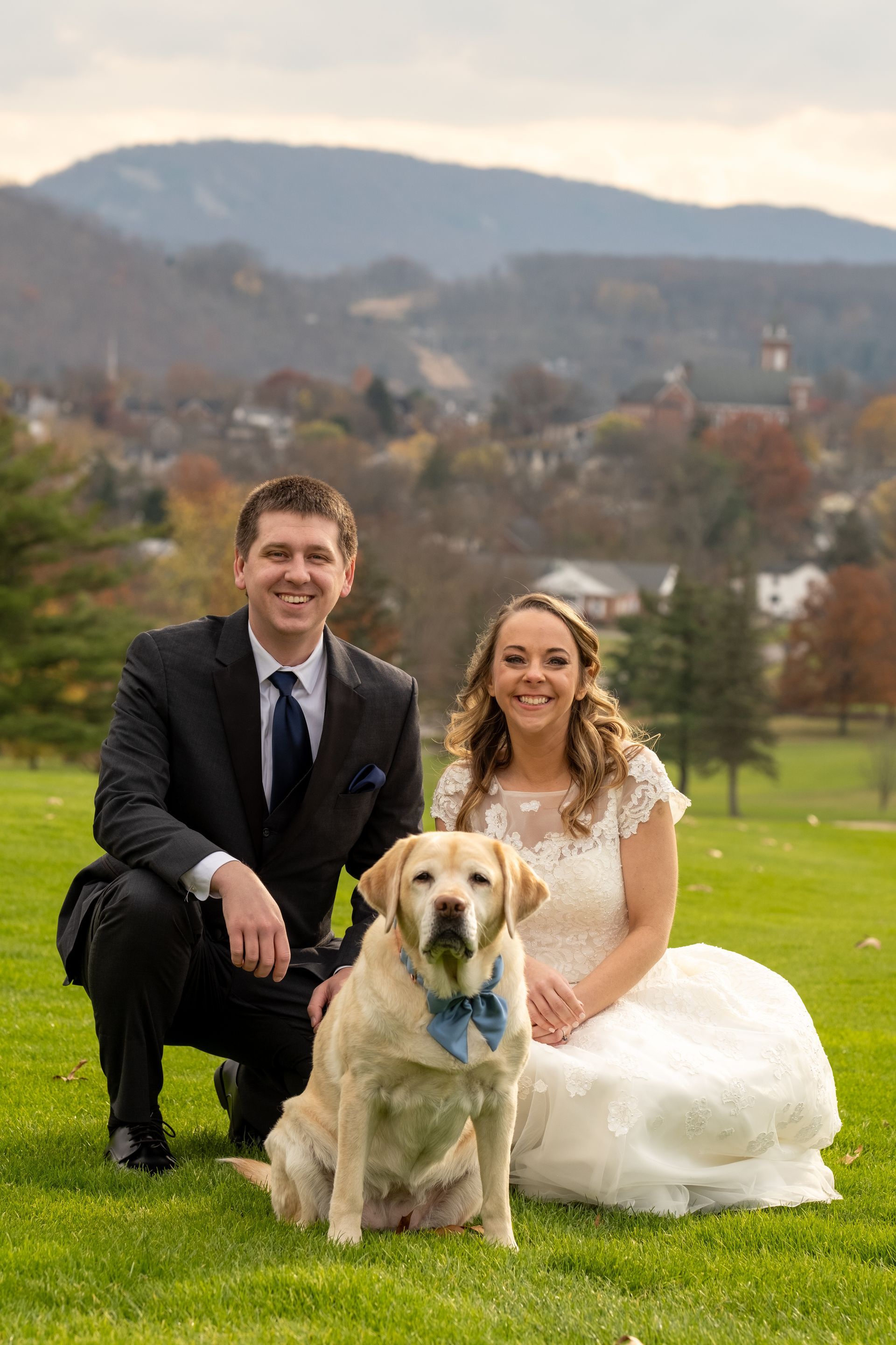 A bride and groom are posing for a picture with their dog taken by Ever After Studio.