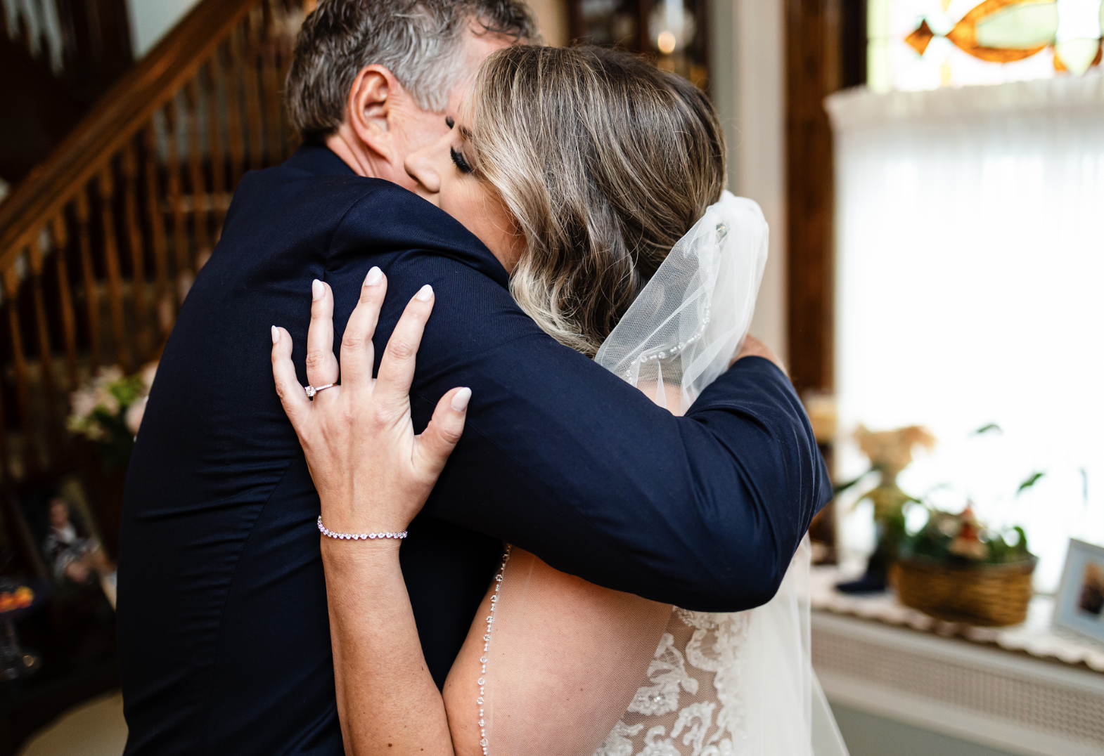 A bride is hugging her father on her wedding day taken by Ever After Studio.