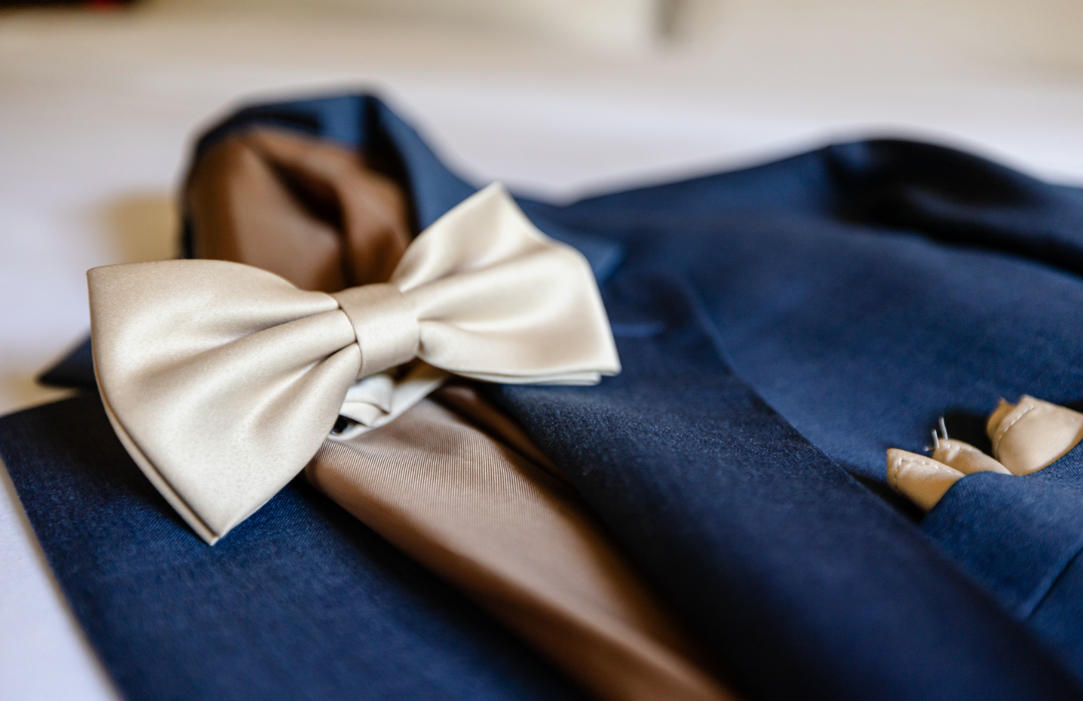A close up of a suit with a bow tie and pocket square taken by Ever After Studio.