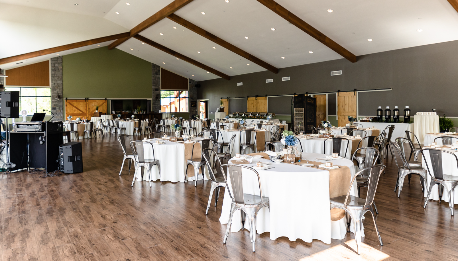 A large room with tables and chairs set up for a wedding reception taken by Ever After Studio.