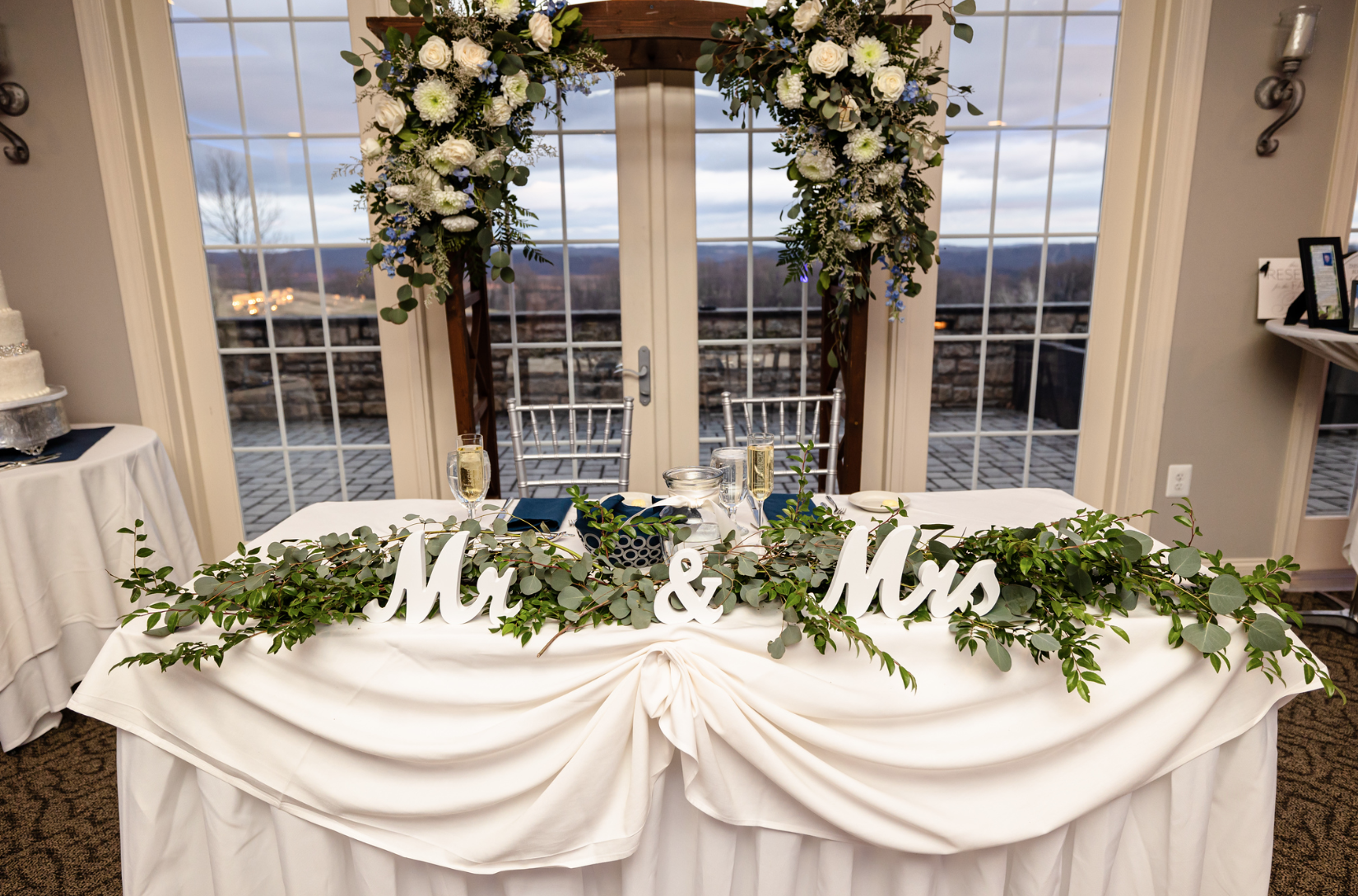 A wedding table with flowers and a sign that says mr. and mrs. taken by Ever After Studio.
