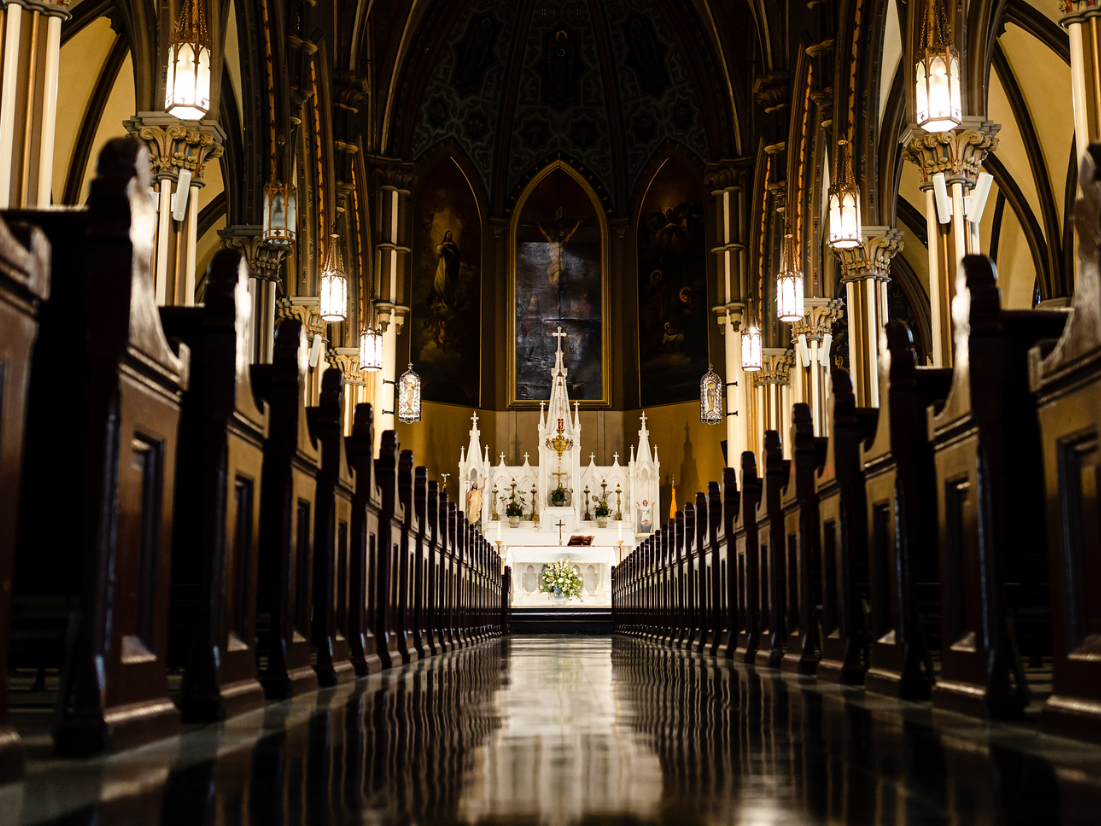 The inside of a church with rows of pews and candles taken by Ever After Studio.