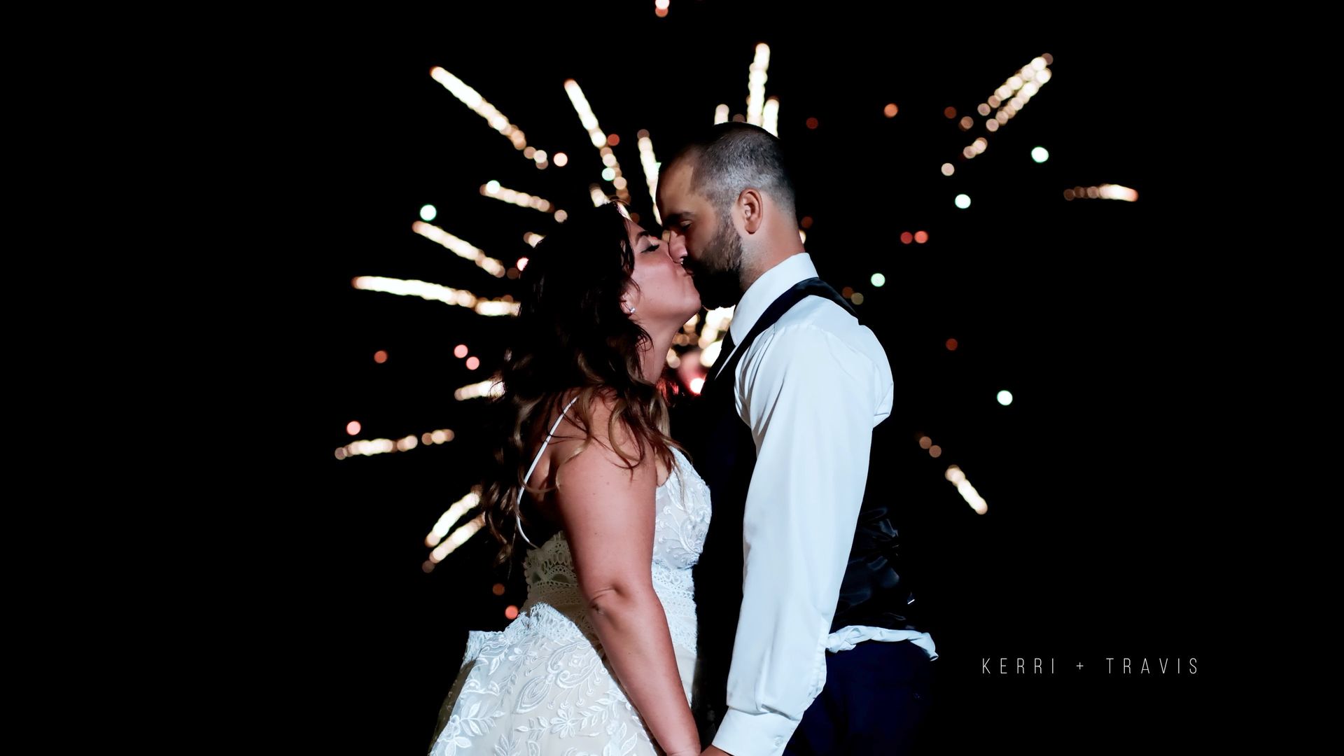 A photo of a bride and groom kissing in front of a fireworks display taken by Ever After Studio.