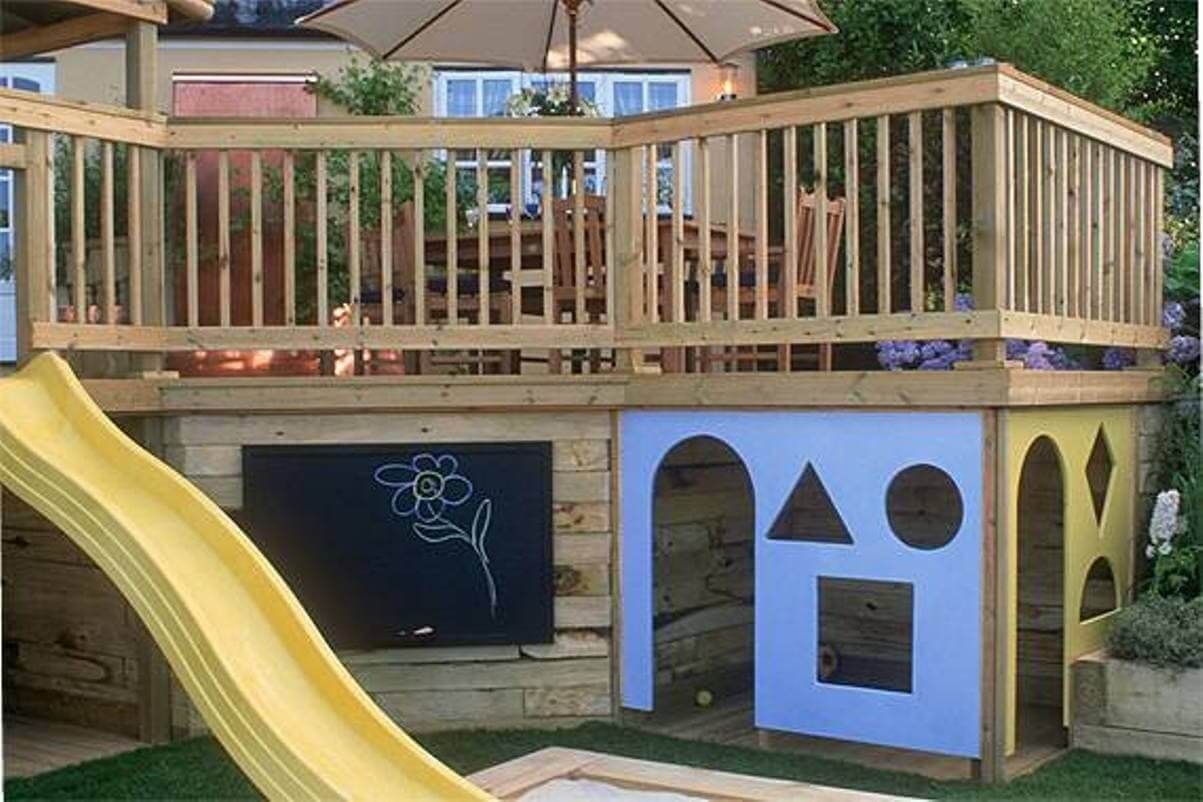 play set under a deck including a slide, a playhouse, and a chalkboard
