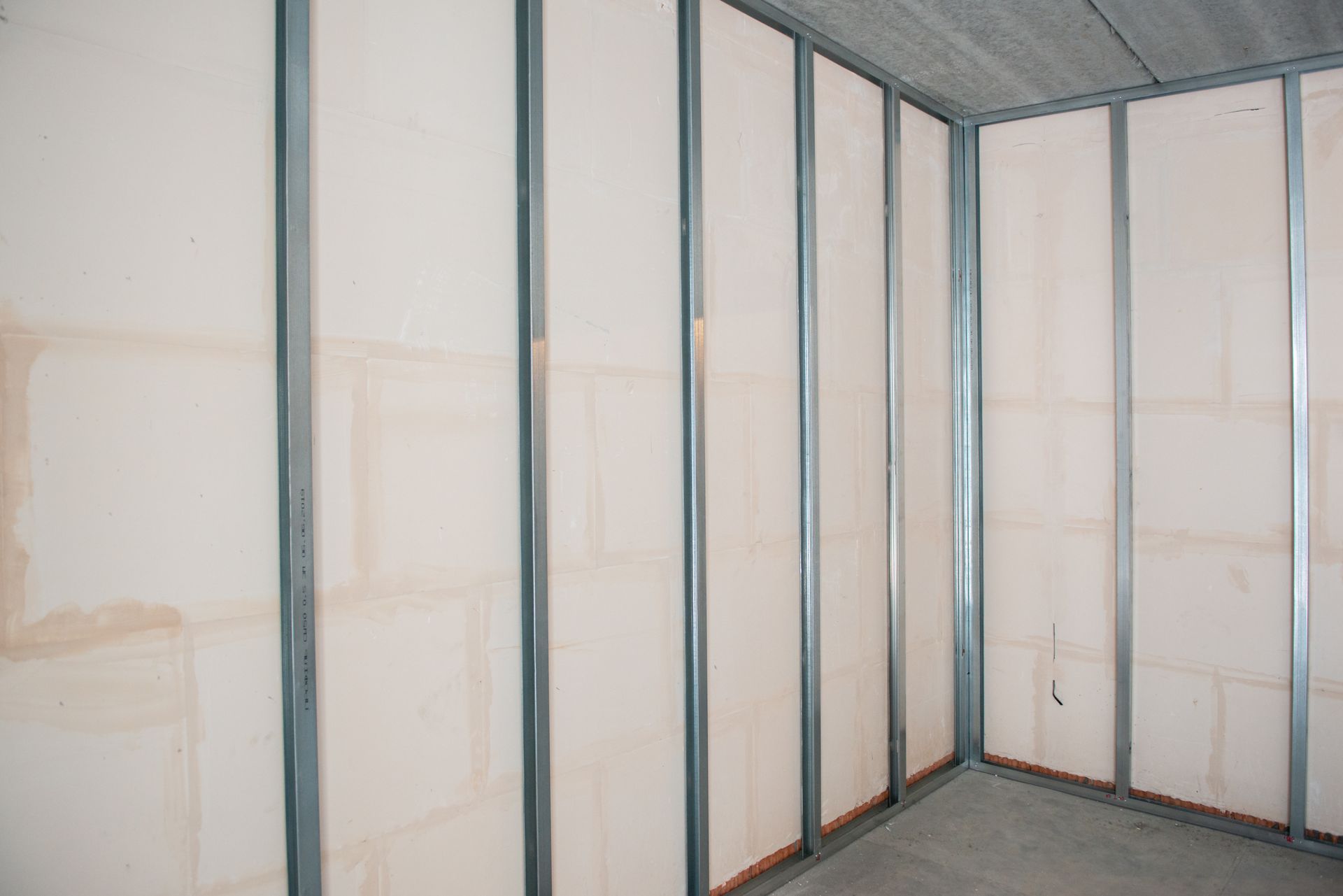 Interior view of room under construction, metal studs and drywall installed.
